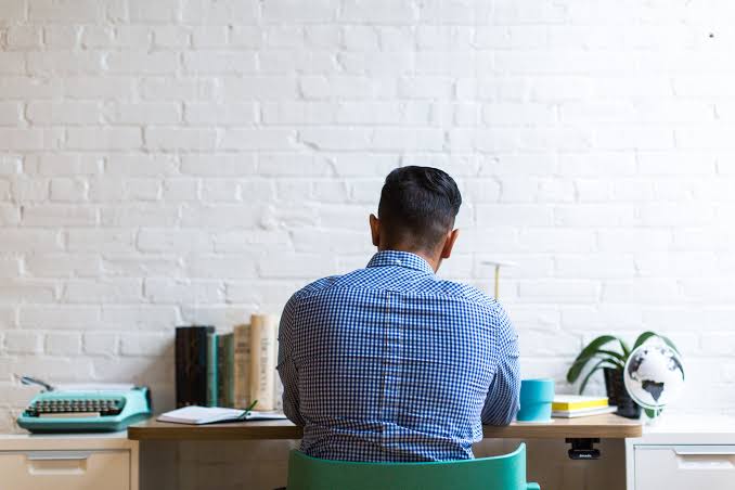 man-working-at-desk-facing-aesthetic-brick-wall